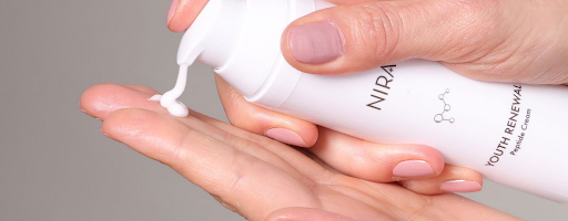 Person using NIRA’s skin renewing peptide cream for its anti-aging benefits